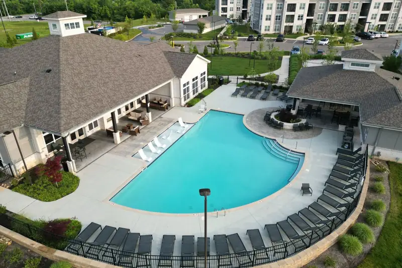 Aerial view of an apartment community pool, lawns and landscaped beds